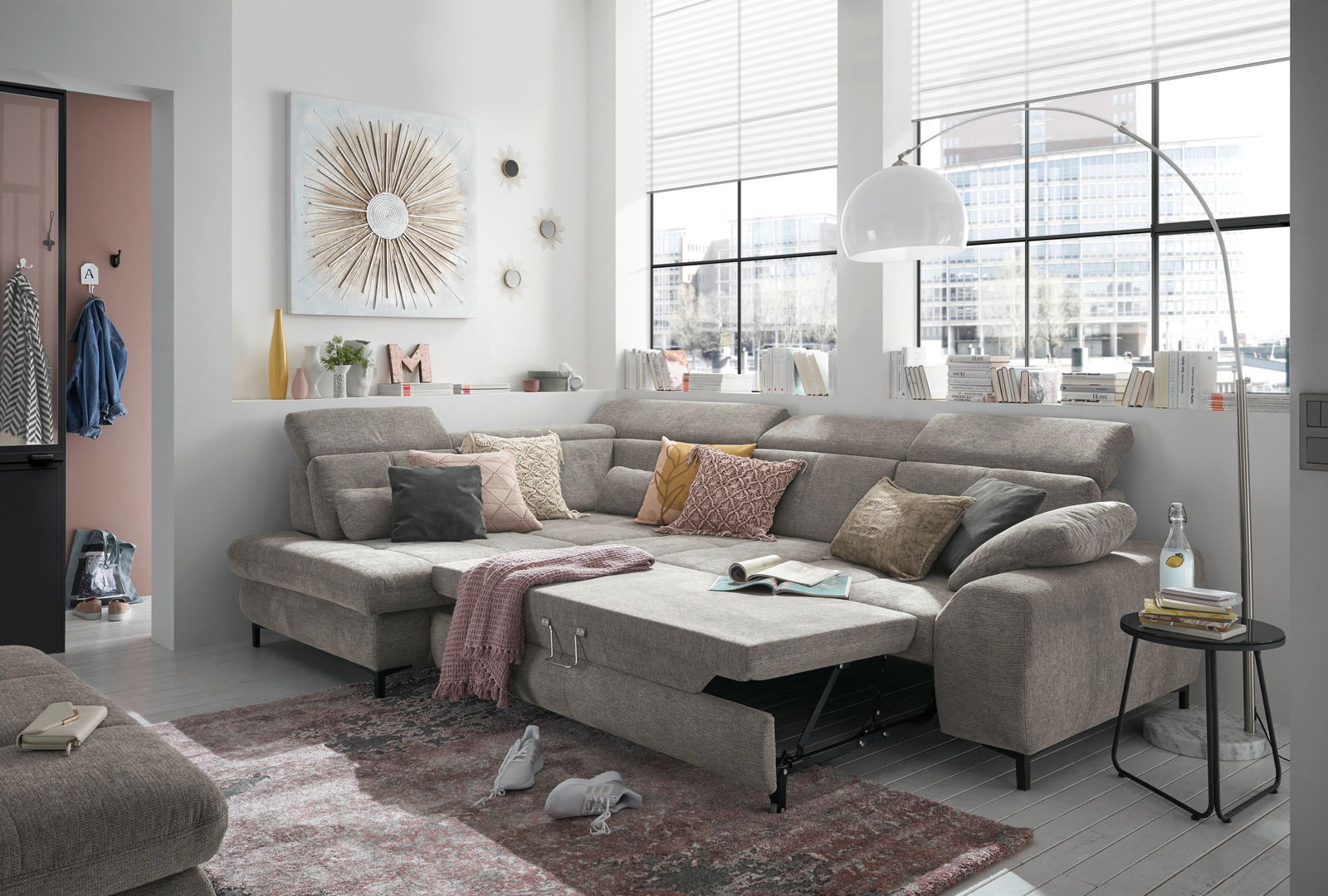 Gemütliche Rundecke in einem modernen Wohnzimmer, mit grauem Stoffbezug und verschiedenen Kissen, aus der Frontalperspektive fotografiert.