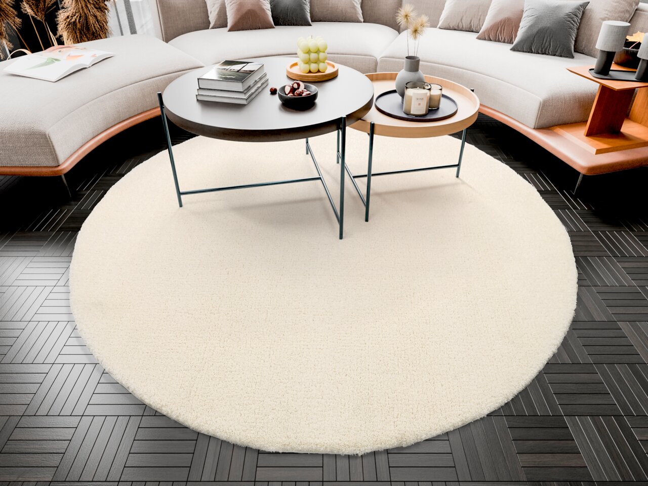 Runder, cremefarbener Teppich mit einem Durchmesser von ca. 150 cm, platziert in einem modernen Wohnzimmer mit dunklem Holzboden und einem eleganten Couchtisch-Arrangement. Perspektive von oben.