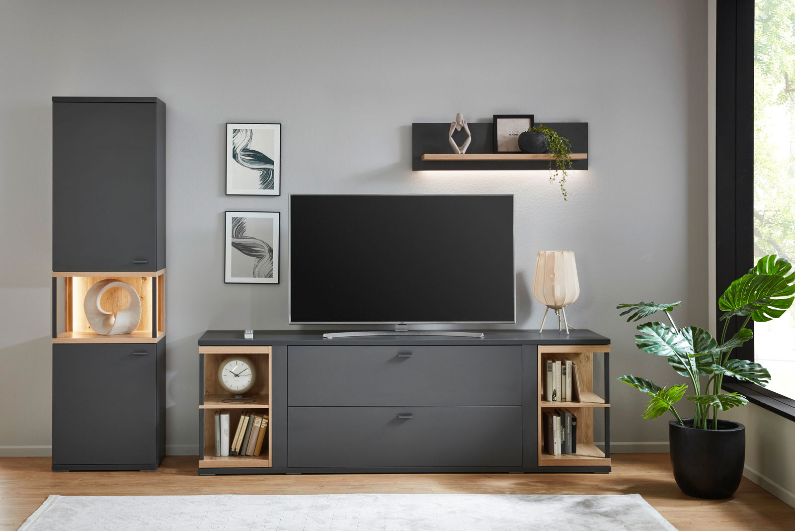 Hom´in Tv-Lowboard MAGOLO Frontale Ansicht eines modernen, dunkelgrauen TV-Lowboards mit offenen Regalfächern an den Seiten, dekoriert mit Büchern und einer Uhr, in einem stilvoll eingerichteten Wohnzimmer.