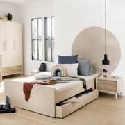 Modernes Schlafzimmer mit großem Bettkasten in hellem Holz, seitliche Perspektive. Der Bettkasten ist teilweise geöffnet und zeigt Stauraum. Dekoriert mit Kissen und Decken in sanften Farben.