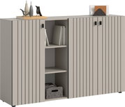 Modernes Sideboard in Beige/Grau mit vertikal gerillten Fronten, drei Türen und offenem Mittelregal mit Büchern und Stoffbox, auf der Deckplatte Deko und Briefhalter; Ansicht schräg von vorne