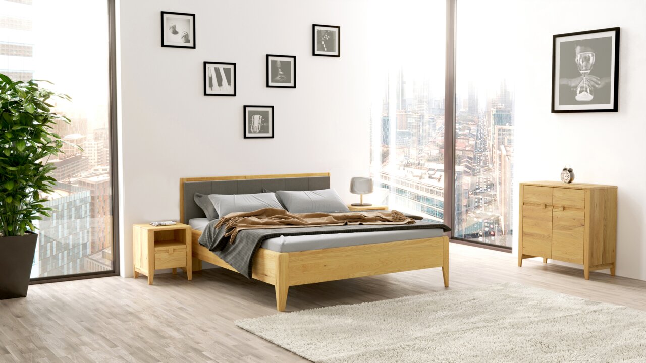 Linea Natura Kommode EPULO Modernes Schlafzimmer mit einem Holzbett, Nachttisch und Kommode in einem hellen Raum mit großen Fenstern, seitliche Perspektive.