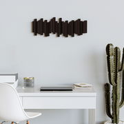 Moderne Wandgarderobe in dunklem Holzdesign, horizontal an einer hellen Wand über einem Schreibtisch mit Kaktus und Büromaterialien angebracht, seitliche Perspektive.