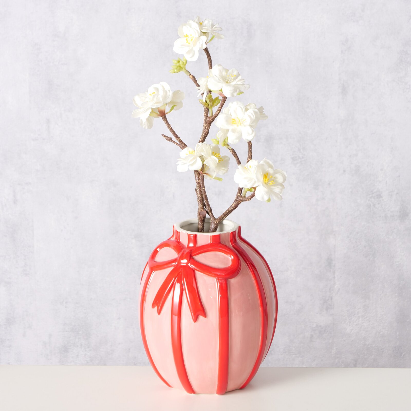 Rote Vase mit Schleifenmuster, gefüllt mit weißen Blumen, seitliche Perspektive