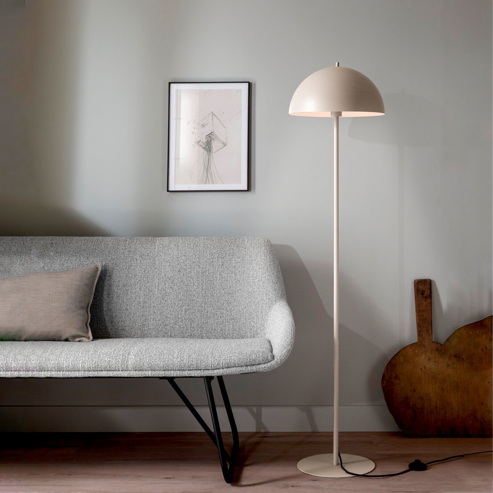 Schöner Wohnen Stehleuchte ALI Beige Stehlampe mit halbkugelförmigem Schirm und rundem Standfuß neben grauem Sofa in modernem Wohnzimmer, Frontansicht auf Augenhöhe.