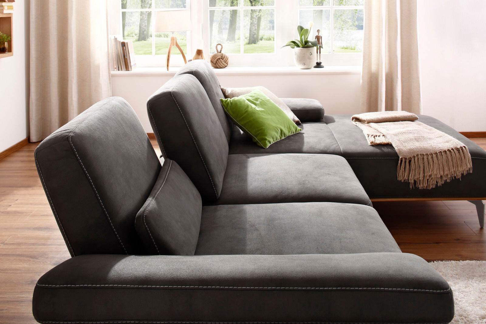 Graue Longchairkombination Valnatura 16580 SPRINT in einem hellen Raum mit Holzboden, seitliche Perspektive, dekoriert mit grünen und beigen Kissen sowie einer Decke.