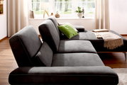 Grijze longchair-set Valnatura 16580 SPRINT in een lichte ruimte met houten vloer, gezien vanaf de zijkant, versierd met groene en beige kussens en een deken.