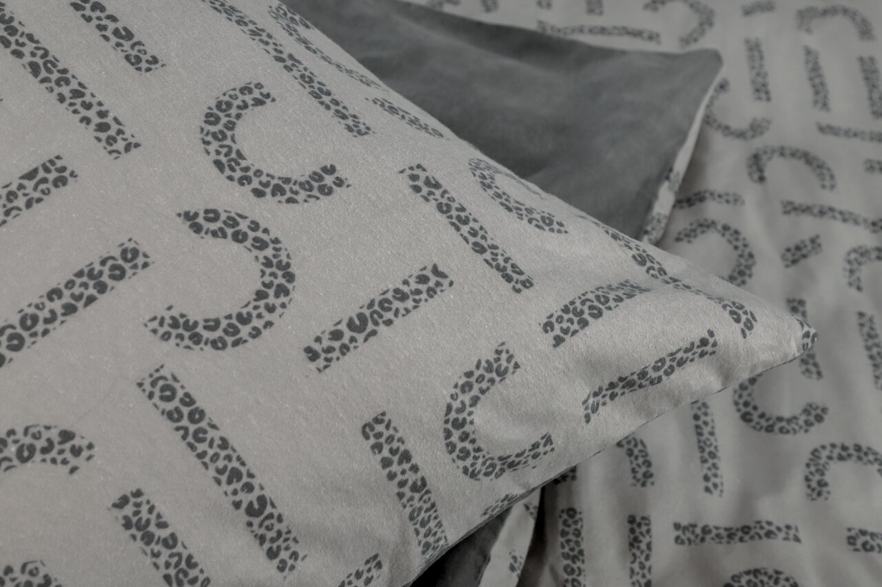 Nahaufnahme einer Bettwäsche mit grauem Hintergrund und schwarzem Leopardenmuster, perspektivisch von oben fotografiert.
