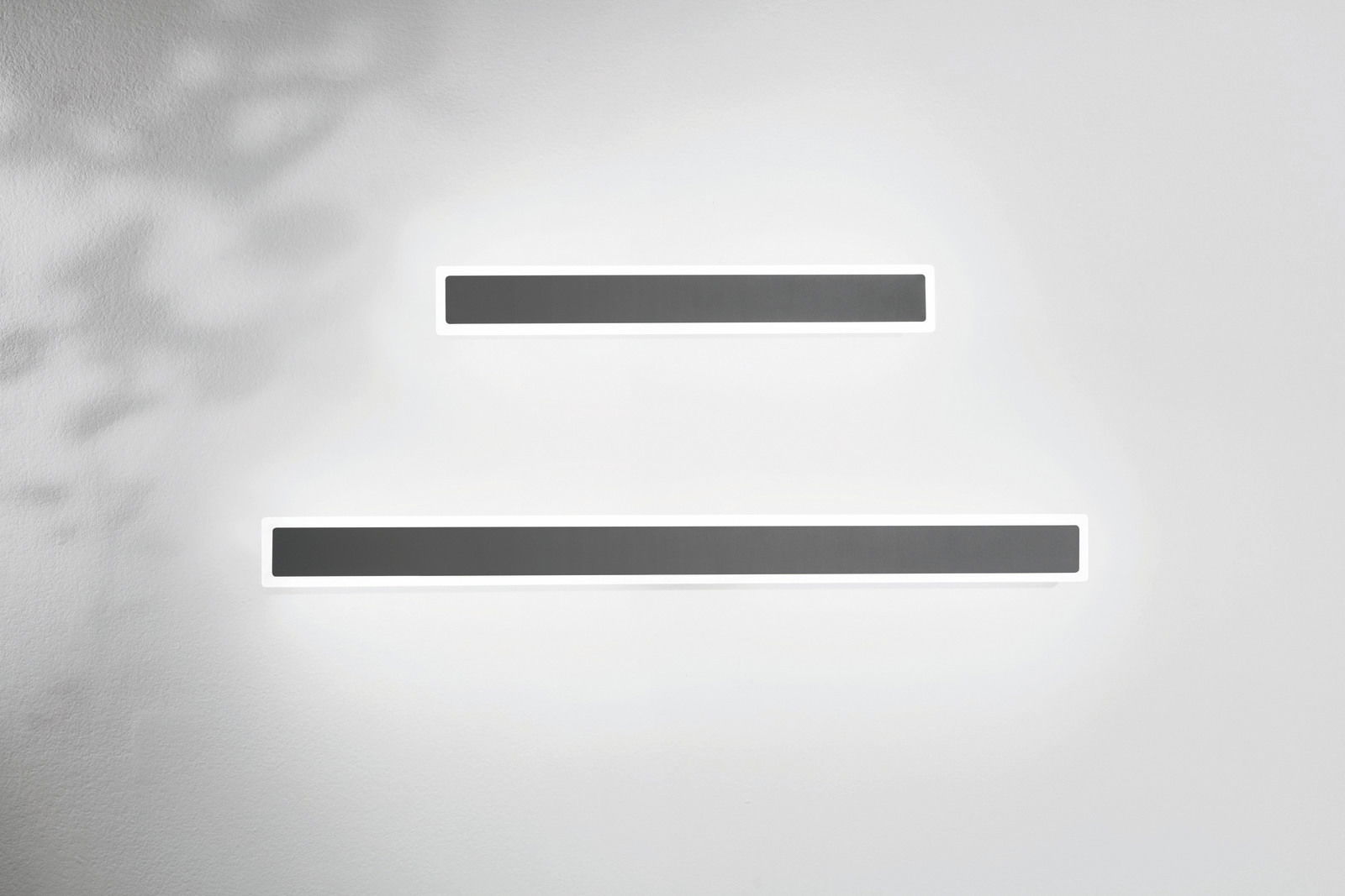 Zwei moderne LED-Außenwandleuchten in rechteckiger Form, an einer weißen Wand montiert, aus der Frontalperspektive betrachtet.