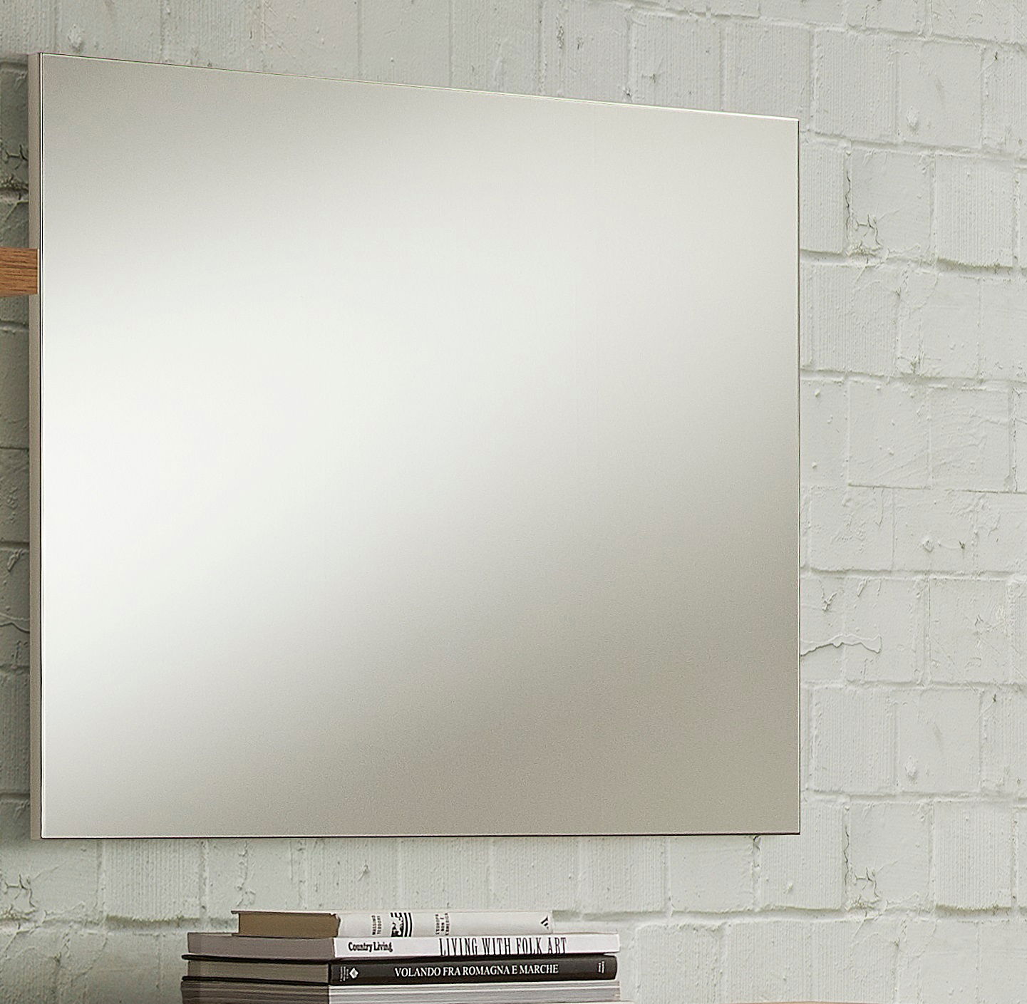 Rechteckiger Wandspiegel vor einer weißen Ziegelwand, seitliche Perspektive