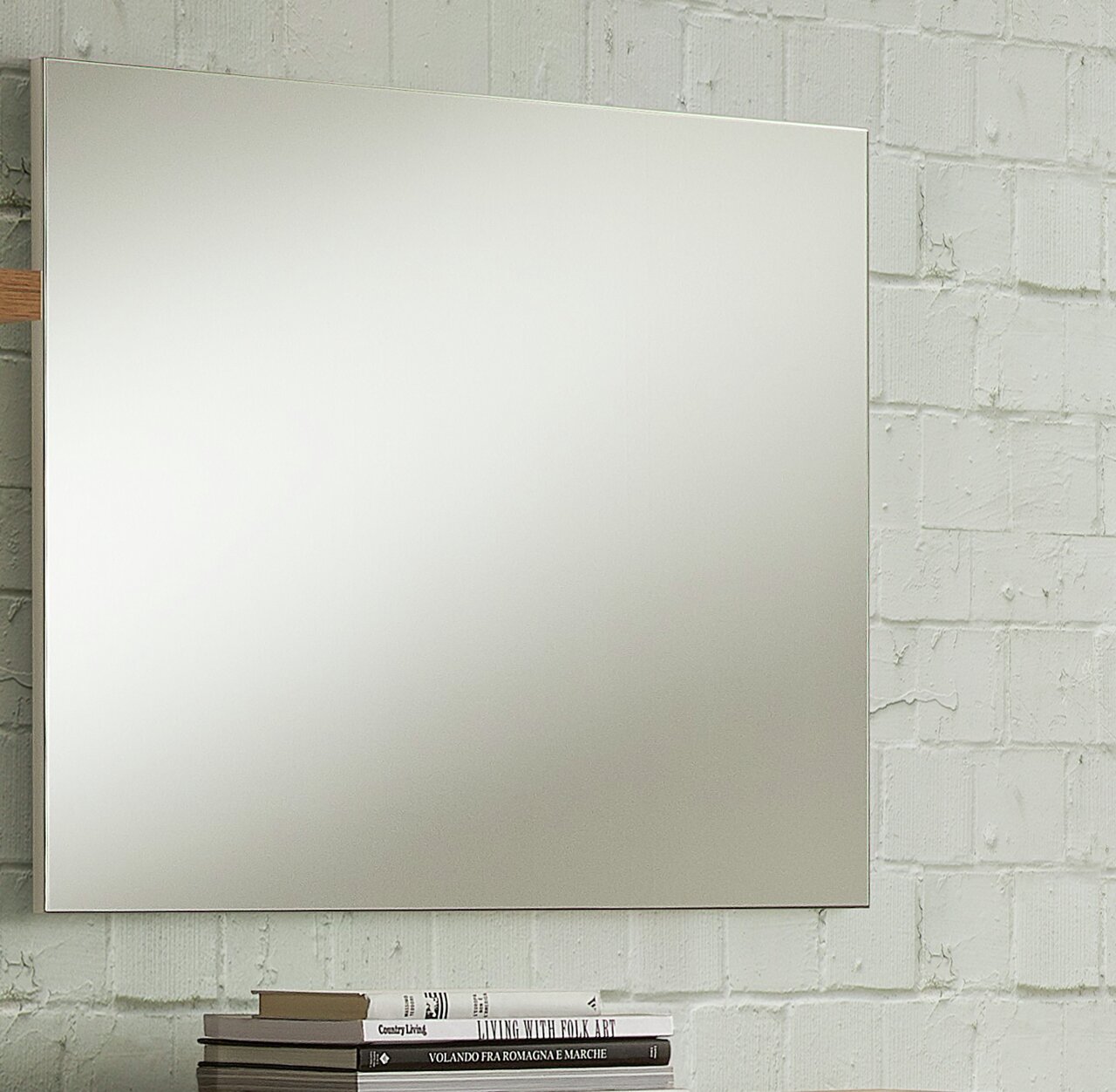 Rechteckiger Wandspiegel vor einer weißen Ziegelwand, seitliche Perspektive