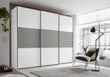 Moderner Schwebetürenschrank in Weiß und Grau, seitliche Perspektive, in einem hellen Raum mit großen Fenstern.
