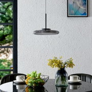 Moderne LED-Hängeleuchte in einem Esszimmer, von der Seite betrachtet, über einem Tisch mit Blumen und Obstkorb.
