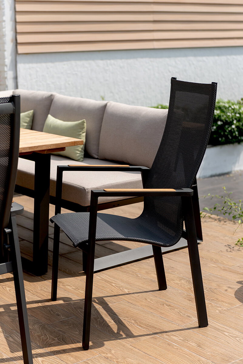 Moderner schwarzer Stapelsessel mit Netzbespannung und Holzarmlehnen auf einer Terrasse, seitliche Perspektive.