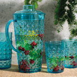 Blaues Kannenset mit Beeren und Minze, von vorne fotografiert, auf einem Tisch im Freien.
