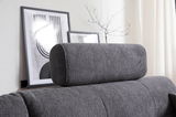 Graue Kopfstütze auf einem Sofa, seitliche Perspektive, mit modernen Kunstwerken im Hintergrund.