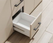 Nahaufnahme eines geöffneten Schubfachs eines Sideboards mit modernen schwarzen Griffen, aus der Vogelperspektive.