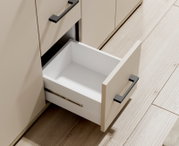 Nahaufnahme eines geöffneten Schubfachs eines Sideboards mit modernen schwarzen Griffen, aus der Vogelperspektive.