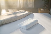 Schlafkissen 61 x 31 cm auf einem Bett, seitliche Perspektive, Sonnenlicht im Hintergrund