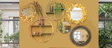 Eine Wand mit mehreren dekorativen Wandspiegeln in verschiedenen Designs, darunter runde Spiegel mit goldenen und natürlichen Rahmen, aus der Frontalperspektive betrachtet.
