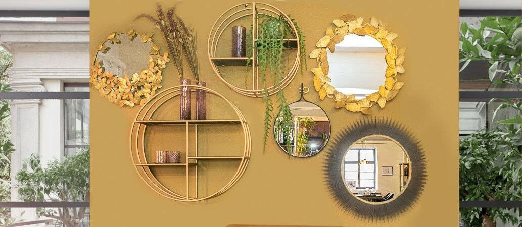 Eine Wand mit mehreren dekorativen Wandspiegeln in verschiedenen Designs, darunter runde Spiegel mit goldenen und natürlichen Rahmen, aus der Frontalperspektive betrachtet.