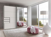 Moderner Schwebetürenschrank mit Spiegel in einem hellen Raum mit Blick auf große Fenster und eine gemütliche Sitzgelegenheit, seitliche Perspektive.