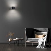 Moderne Wandleuchte PURE CLIPSE in schwarzem Design, an einer dunklen Wand montiert, mit indirekter Beleuchtung nach oben und unten, im stilvollen Wohnzimmerambiente.