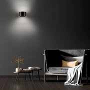 Moderne Wandleuchte PURE CLIPSE in schwarzem Design, an einer dunklen Wand montiert, mit indirekter Beleuchtung nach oben und unten, im stilvollen Wohnzimmerambiente.