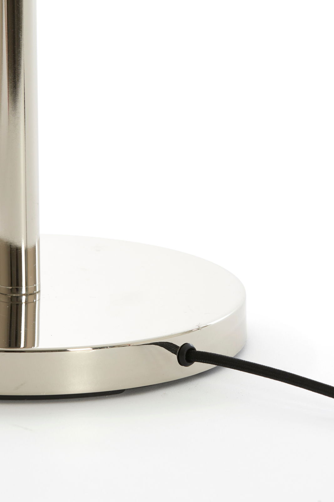 Nahaufnahme des Sockels einer Stehleuchte mit glänzender Metalloberfläche und schwarzem Kabel.