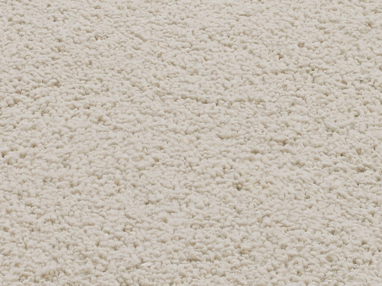 Nahaufnahme eines cremefarbenen Uni-Teppichs mit weicher, flauschiger Textur.