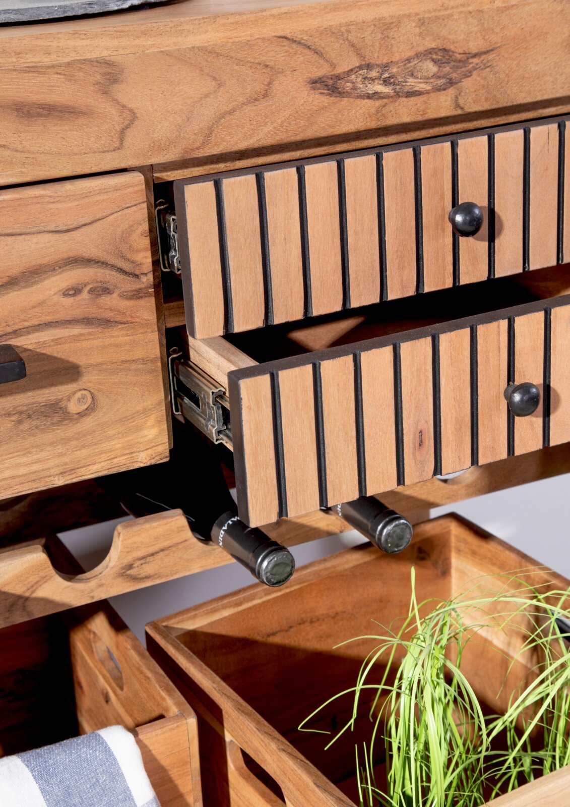 Nahaufnahme eines Servierwagens aus Holz mit geöffneten Schubladen, Weinflaschenhalter und Aufbewahrungsboxen, aus der Perspektive von vorne.