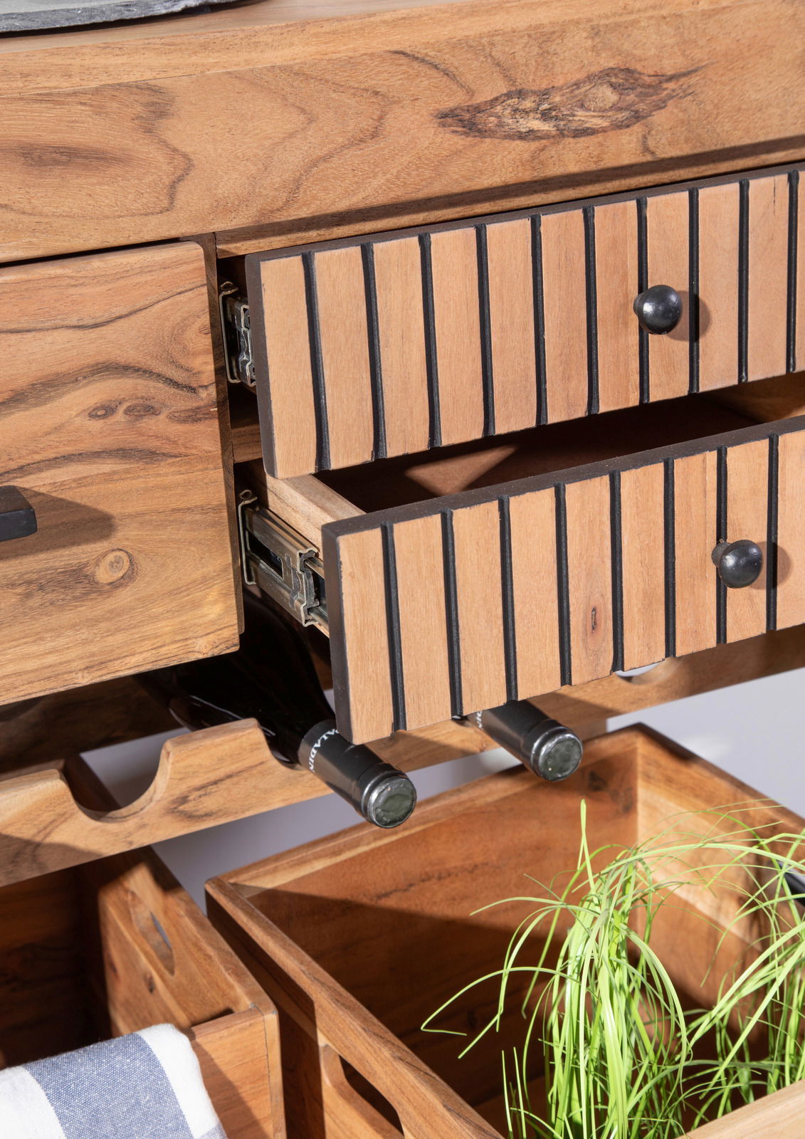 Nahaufnahme eines Servierwagens aus Holz mit geöffneten Schubladen, Weinflaschenhalter und Aufbewahrungsboxen, aus der Perspektive von vorne.