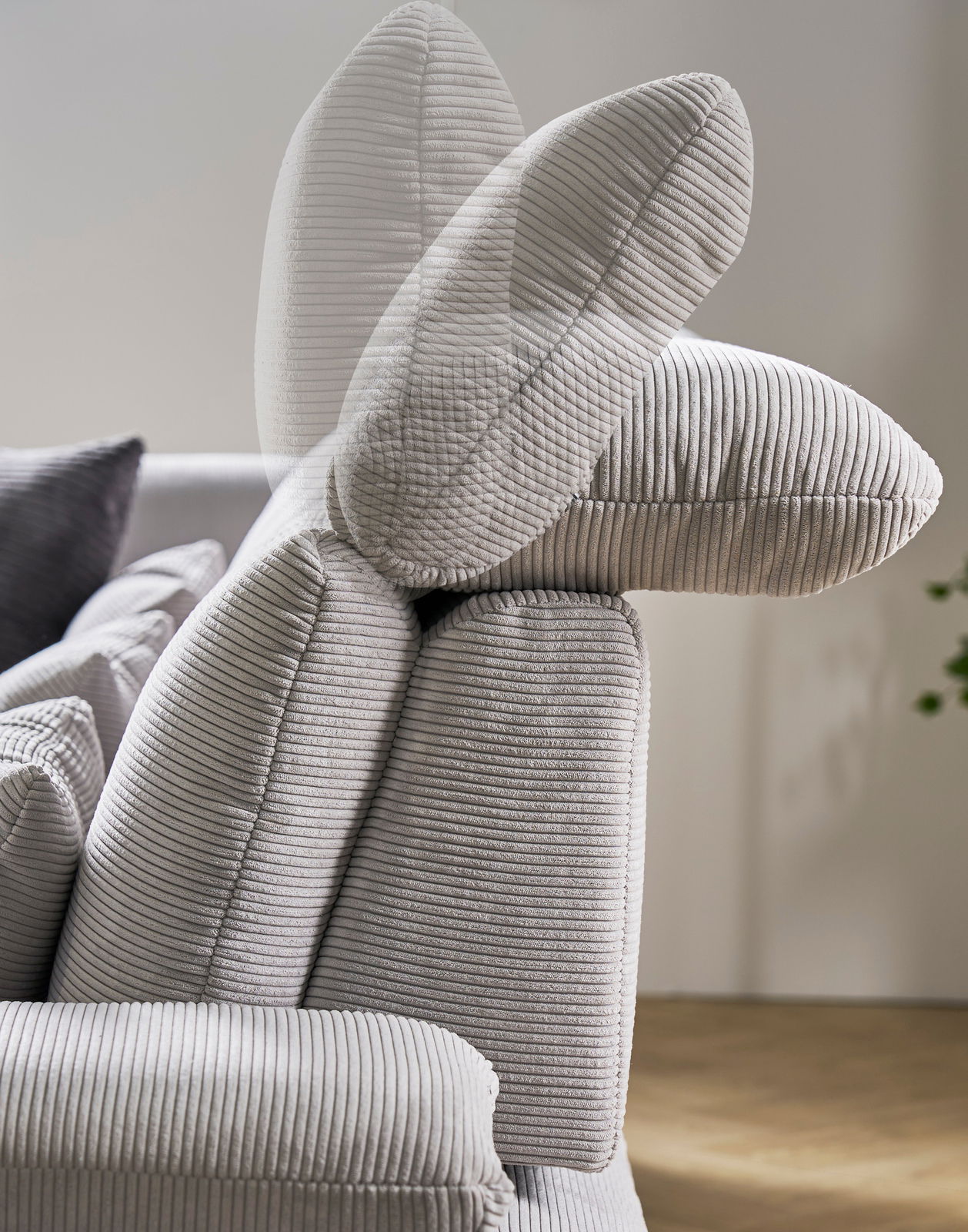 Nahaufnahme einer verstellbaren Rückenlehne eines grauen Sofas mit geripptem Stoffbezug, seitliche Perspektive
