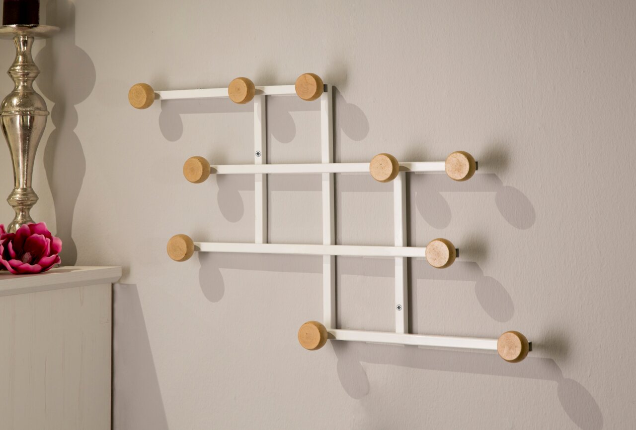 Moderner Garderobenhaken mit mehreren Holzknöpfen an einer weißen Metallstruktur, seitliche Perspektive.