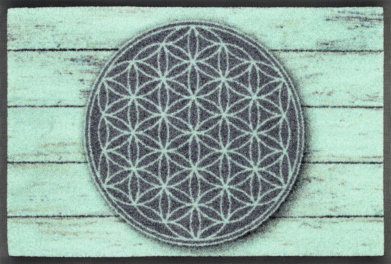 Teppich mit geometrischem Muster in der Mitte, das aus sich wiederholenden Kreisen besteht, auf einem Hintergrund, der wie verwittertes Holz aussieht. Draufsicht.