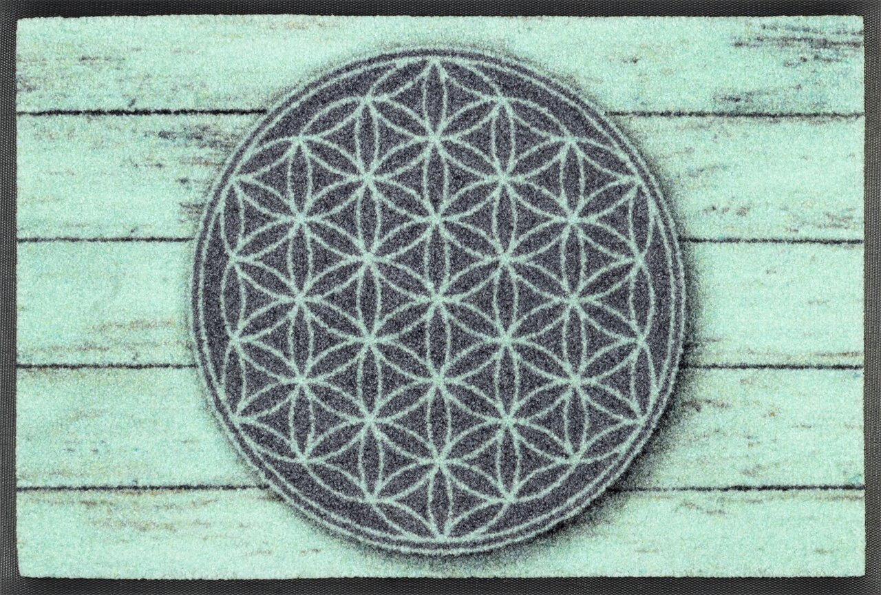 Tapijt met een geometrisch patroon in het midden, bestaande uit zich herhalende cirkels, op een achtergrond die eruitziet als verweerd hout. Bovenaanzicht.
