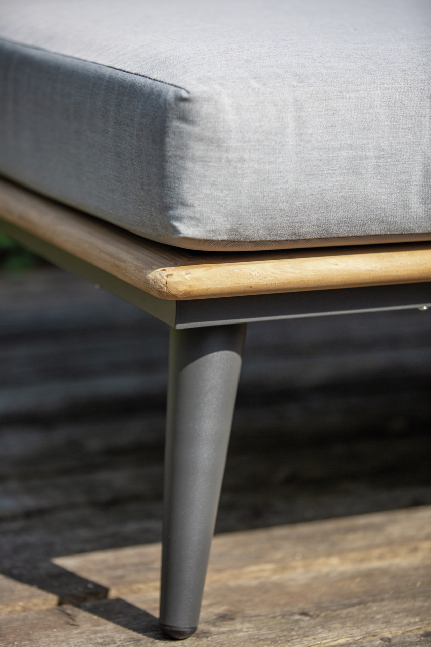 Nahaufnahme eines Loungemöbels mit grauem Kissen, Holzrahmen und Metallbein, seitliche Perspektive