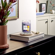 Frontalansicht einer brennenden Yankee Candle Lemon Lavender Duftkerze mit zwei Dochten im großen Glas, dekorativ auf Büchern in einem stilvollen Wohnambiente platziert