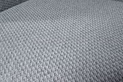 Nahaufnahme eines grauen, strukturierten Stoffes, der für einen Sessel verwendet wird, aus einer schrägen Perspektive aufgenommen.