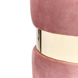 Nahaufnahme eines rosa Hockers mit goldener Metallverzierung in der Mitte, seitliche Perspektive.