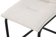 Nahaufnahme eines gepolsterten Sitzkissens in hellem Beige auf schwarzem Metallgestell, schräg von oben fotografiert