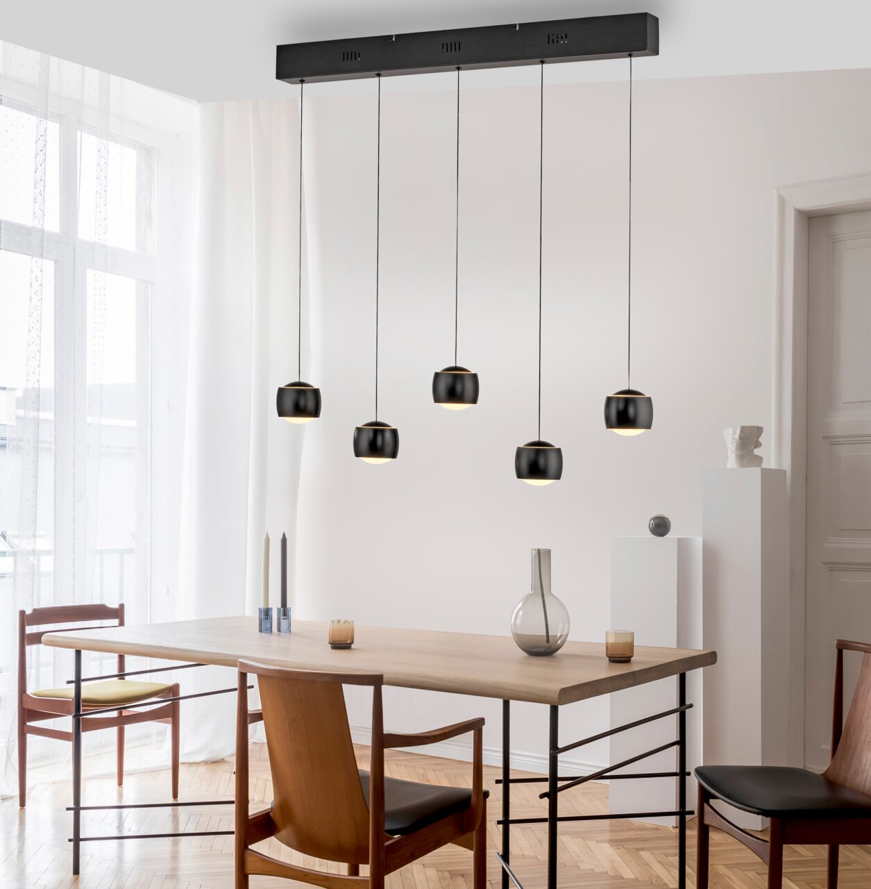 Moderne hanglamp BALLINI met vijf zwarte lampenkappen, hangend boven een eettafel in een lichte ruimte, zijaanzicht.