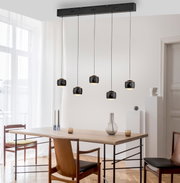 Moderne hanglamp BALLINI met vijf zwarte lampenkappen, hangend boven een eettafel in een lichte ruimte, zijaanzicht.