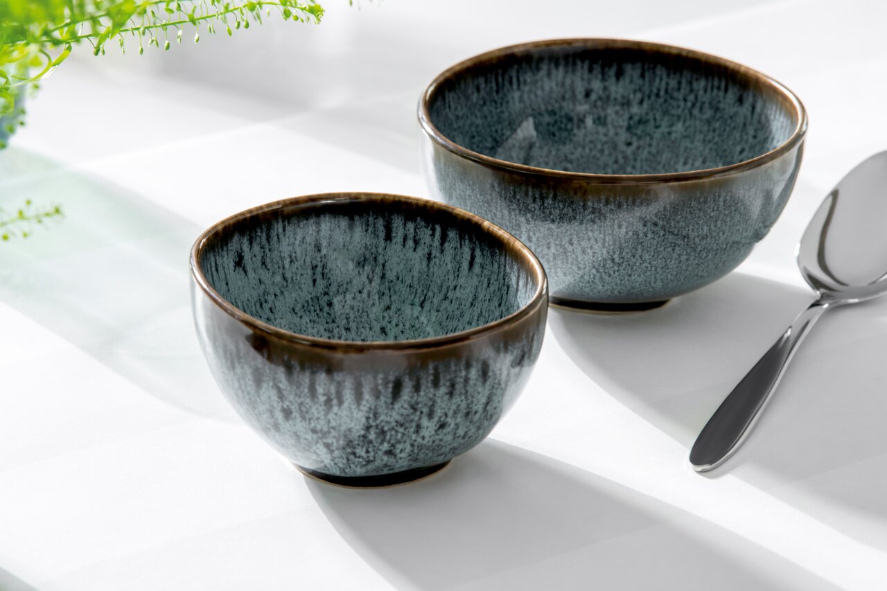 Like by Villeroy & Boch Bowl LAVE GLACE Zwei blaue Dessertschalen aus Keramik mit glänzender Oberfläche, von schräg oben fotografiert, neben einem Löffel auf einem weißen Tisch.