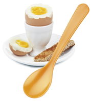 Ein goldener Eierlöffel neben einem weichgekochten Ei im Eierbecher auf einem Teller mit Toaststreifen, aus der Seitenperspektive.