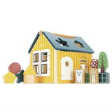 Holz-Steckhaus mit gelben Wänden und blauen Dach, umgeben von bunten Steckformen und Tierfiguren, seitliche Perspektive
