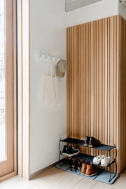 Wandgarderobe mit Haken, an der eine Tasche und eine Mütze hängen, aus seitlicher Perspektive fotografiert.