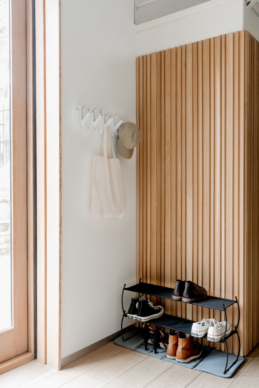 Wandgarderobe mit Haken, an der eine Tasche und eine Mütze hängen, aus seitlicher Perspektive fotografiert.