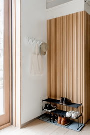 Wandgarderobe mit Haken, an der eine Tasche und eine Mütze hängen, aus seitlicher Perspektive fotografiert.
