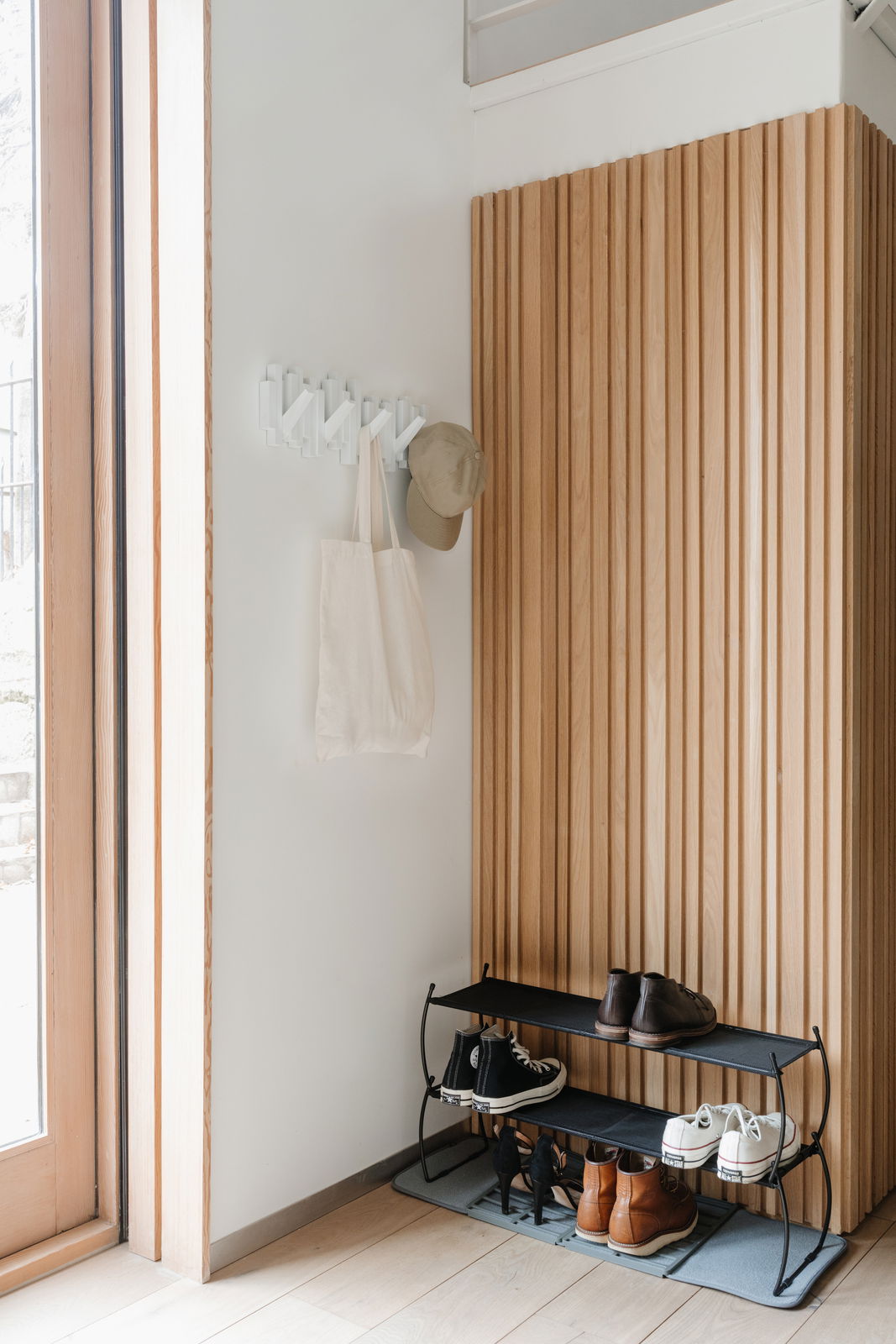 Wandgarderobe mit Haken, an der eine Tasche und eine Mütze hängen, aus seitlicher Perspektive fotografiert.